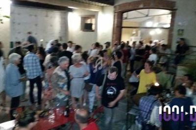 Groupe de personnes rassemblées dans une cour extérieure en soirée, discutant et partageant un moment convivial.