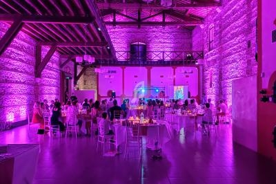 Salle de réception illuminée de lumières violettes, avec des invités assis à des tables rondes.