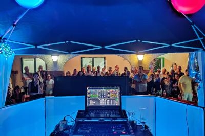 Vue depuis une cabine de DJ éclairée, face à une foule rassemblée sous un éclairage nocturne.