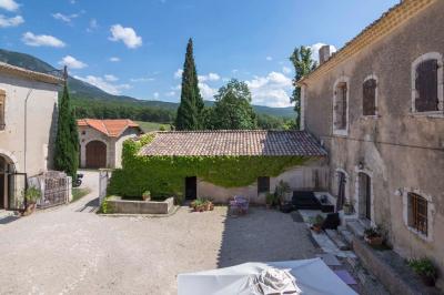 Vue sur un lac entouré de collines verdoyantes à travers une fenêtre ouverte avec des volets en bois.