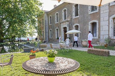 Vue sur un lac entouré de collines verdoyantes à travers une fenêtre ouverte avec des volets en bois.