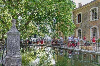 Vue sur un lac entouré de collines verdoyantes à travers une fenêtre ouverte avec des volets en bois.