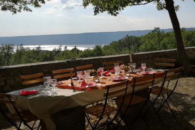 Vue sur un lac entouré de collines verdoyantes à travers une fenêtre ouverte avec des volets en bois.
