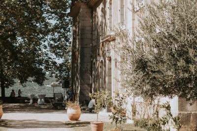 Vue sur un lac entouré de collines verdoyantes à travers une fenêtre ouverte avec des volets en bois.