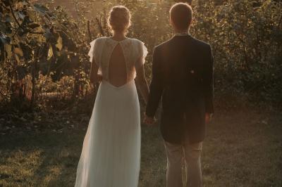 Vue sur un lac entouré de collines verdoyantes à travers une fenêtre ouverte avec des volets en bois.