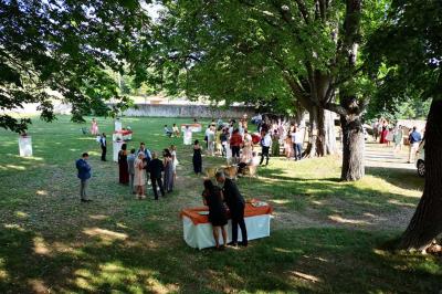 Vue sur un lac entouré de collines verdoyantes à travers une fenêtre ouverte avec des volets en bois.