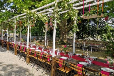 Vue sur un lac entouré de collines verdoyantes à travers une fenêtre ouverte avec des volets en bois.