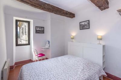 Vue sur un lac entouré de collines verdoyantes à travers une fenêtre ouverte avec des volets en bois.