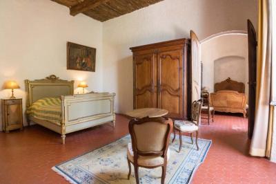 Vue sur un lac entouré de collines verdoyantes à travers une fenêtre ouverte avec des volets en bois.
