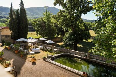 Vue sur un lac entouré de collines verdoyantes à travers une fenêtre ouverte avec des volets en bois.