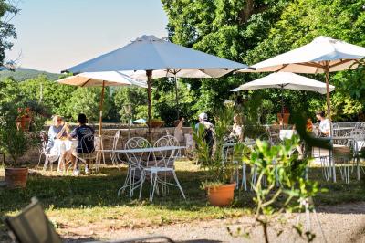 Vue sur un lac entouré de collines verdoyantes à travers une fenêtre ouverte avec des volets en bois.