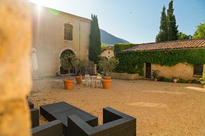 Vue sur un lac entouré de collines verdoyantes à travers une fenêtre ouverte avec des volets en bois.