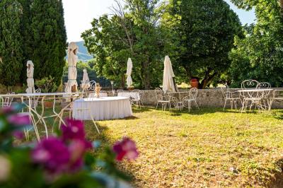 Vue sur un lac entouré de collines verdoyantes à travers une fenêtre ouverte avec des volets en bois.