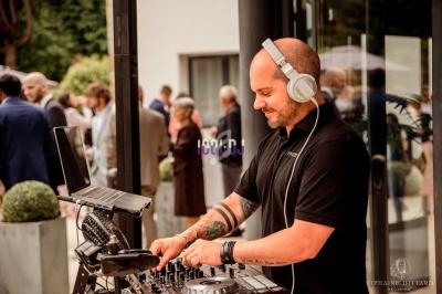 Un DJ mixant de la musique sur une table de mixage lors d'un événement en extérieur avec des invités en arrière-plan.