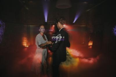 Un couple danse dans une salle sombre éclairée par des lumières colorées et des effets de fumée.