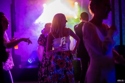 Personnes dansant dans une ambiance festive avec éclairages colorés et fumée en arrière-plan.