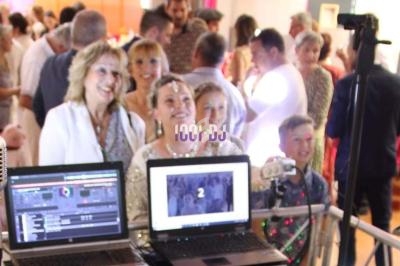Des invités souriants posent devant un photobooth lors d'une fête, avec un ordinateur et un micro au premier plan.
