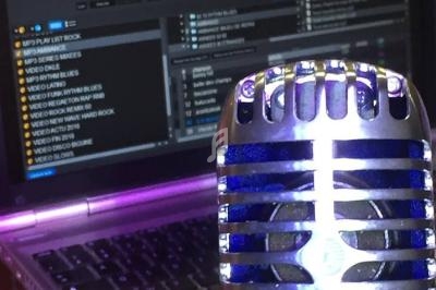 Microphone rétro argenté en gros plan devant un ordinateur portable affichant une interface de mixage audio.