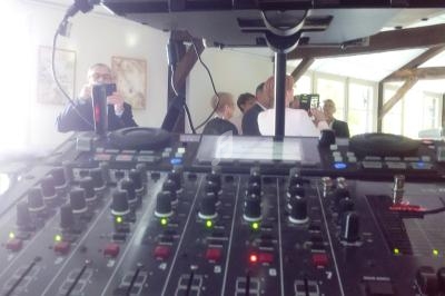 Table de mixage audio en premier plan avec un écran de contrôle vidéo et des personnes en arrière-plan dans une salle…