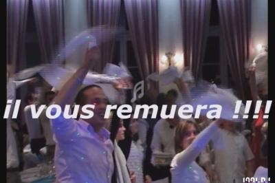 Des personnes dansent en agitant des serviettes blanches dans une salle éclairée avec des rideaux et des lumières tamisées.