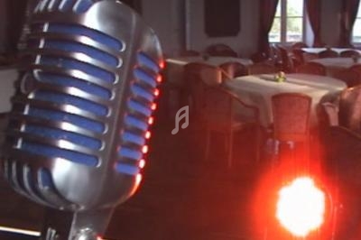 Micro vintage en gros plan devant une salle de réception vide avec des tables rondes et un éclairage tamisé.