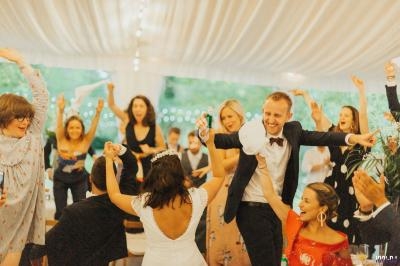 Des invités dansent et célèbrent joyeusement sous une tente lumineuse lors d'une réception de mariage.