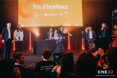 Des personnes sur scène lors d'une remise de prix, avec un écran affichant ’Prix d'Excellence’ en arrière-plan.