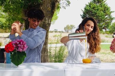 Deux personnes préparent des cocktails en plein air, avec des fleurs et des fruits disposés sur un comptoir blanc.