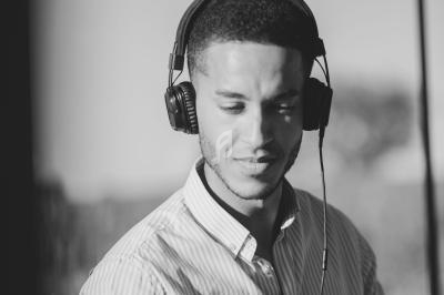 Un homme portant un casque audio regarde un écran d'ordinateur portable dans un environnement lumineux.