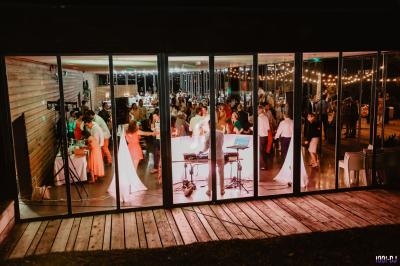 Vue d'une salle de réception animée avec des invités dansant et discutant, éclairée par des lumières chaleureuses.
