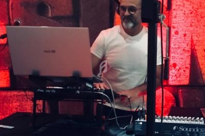 Un homme mixe de la musique sur un ordinateur portable et une table de mixage dans un environnement éclairé en rouge.