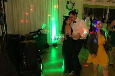 Un couple danse sur une piste éclairée de lumières colorées lors d'une soirée festive en intérieur.