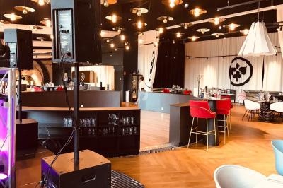 Salle de restaurant moderne avec mobilier coloré, éclairage suspendu et parquet en bois clair.