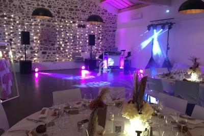 Salle de réception décorée pour un événement, avec tables dressées, éclairages colorés et espace pour la musique.