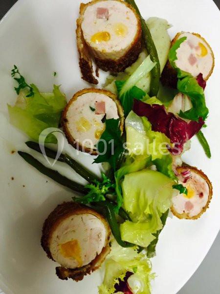 Roulés de volaille farcis accompagnés de haricots verts et d'un mélange de salade verte sur une assiette blanche.