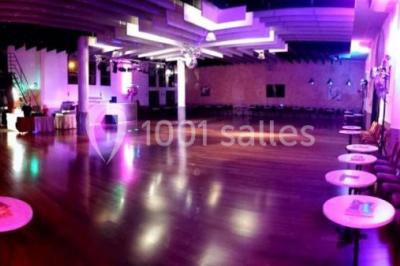 Salle décorée pour Noël avec une scène équipée de matériel audio, des décorations festives et une statue du Père Noël.