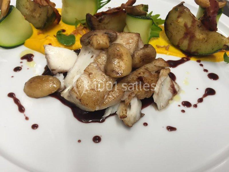 Filet de poisson accompagné de champignons, purée de légumes et légumes grillés, dressé avec une sauce au vin rouge.