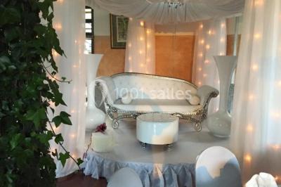 Salle décorée pour Noël avec une scène équipée de matériel audio, des décorations festives et une statue du Père Noël.