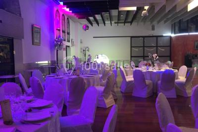 Salle décorée pour Noël avec une scène équipée de matériel audio, des décorations festives et une statue du Père Noël.