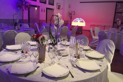 Salle décorée pour Noël avec une scène équipée de matériel audio, des décorations festives et une statue du Père Noël.