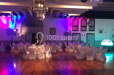 Salle décorée pour Noël avec une scène équipée de matériel audio, des décorations festives et une statue du Père Noël.