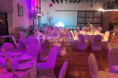 Salle décorée pour Noël avec une scène équipée de matériel audio, des décorations festives et une statue du Père Noël.