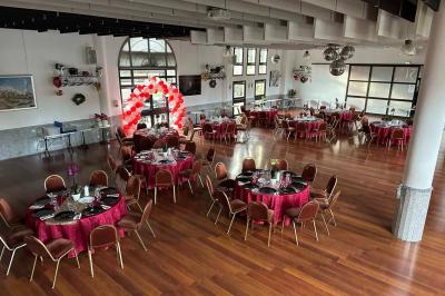 Salle décorée pour Noël avec une scène équipée de matériel audio, des décorations festives et une statue du Père Noël.