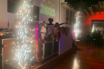 Salle décorée pour Noël avec une scène équipée de matériel audio, des décorations festives et une statue du Père Noël.