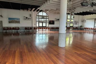 Salle décorée pour Noël avec une scène équipée de matériel audio, des décorations festives et une statue du Père Noël.