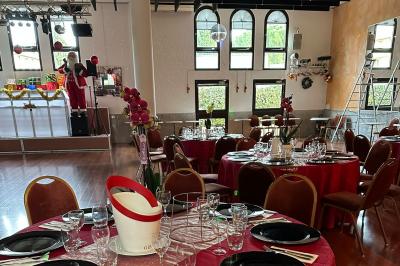 Salle décorée pour Noël avec une scène équipée de matériel audio, des décorations festives et une statue du Père Noël.