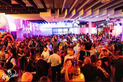 Salle décorée pour Noël avec une scène équipée de matériel audio, des décorations festives et une statue du Père Noël.