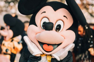 Plateforme circulaire avec un anneau lumineux sur pied, installée sur une pelouse devant un mur en pierre couvert de lierre.