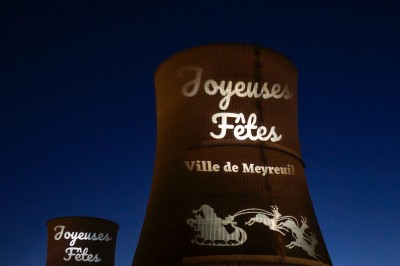 Plateforme circulaire avec un anneau lumineux sur pied, installée sur une pelouse devant un mur en pierre couvert de lierre.