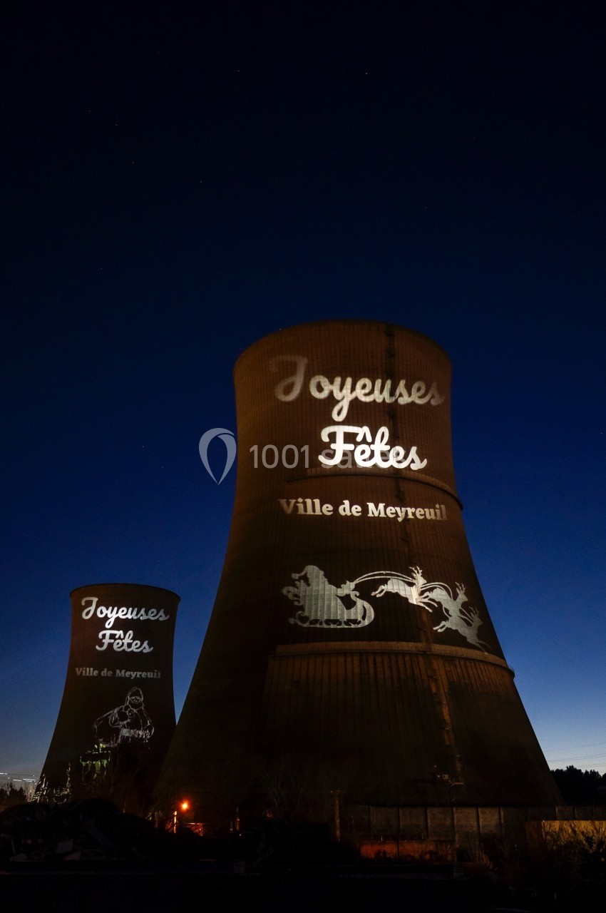 Tours de refroidissement illuminées par des projections de vœux festifs et motifs décoratifs, de nuit.